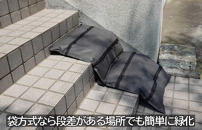 段差のある階段状の床面に対して、袋方式の緑化ユニットを折り曲げて設置している様子を示す写真。